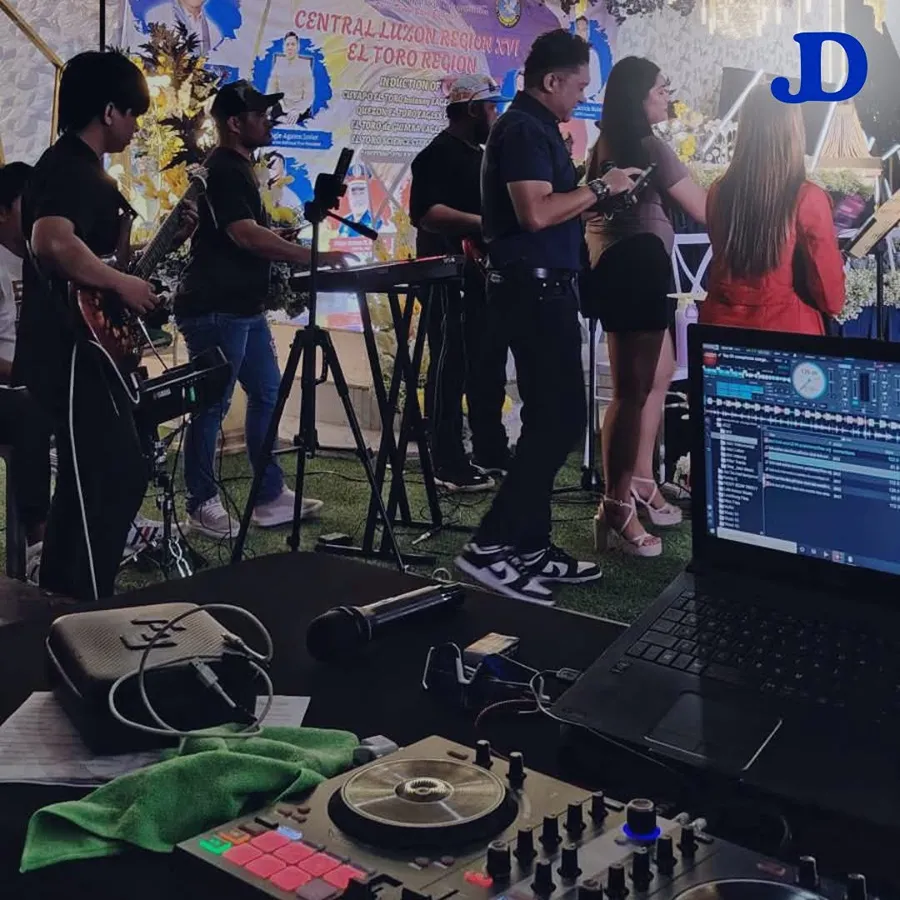 Live band and DJ performing on stage with string lights draped overhead