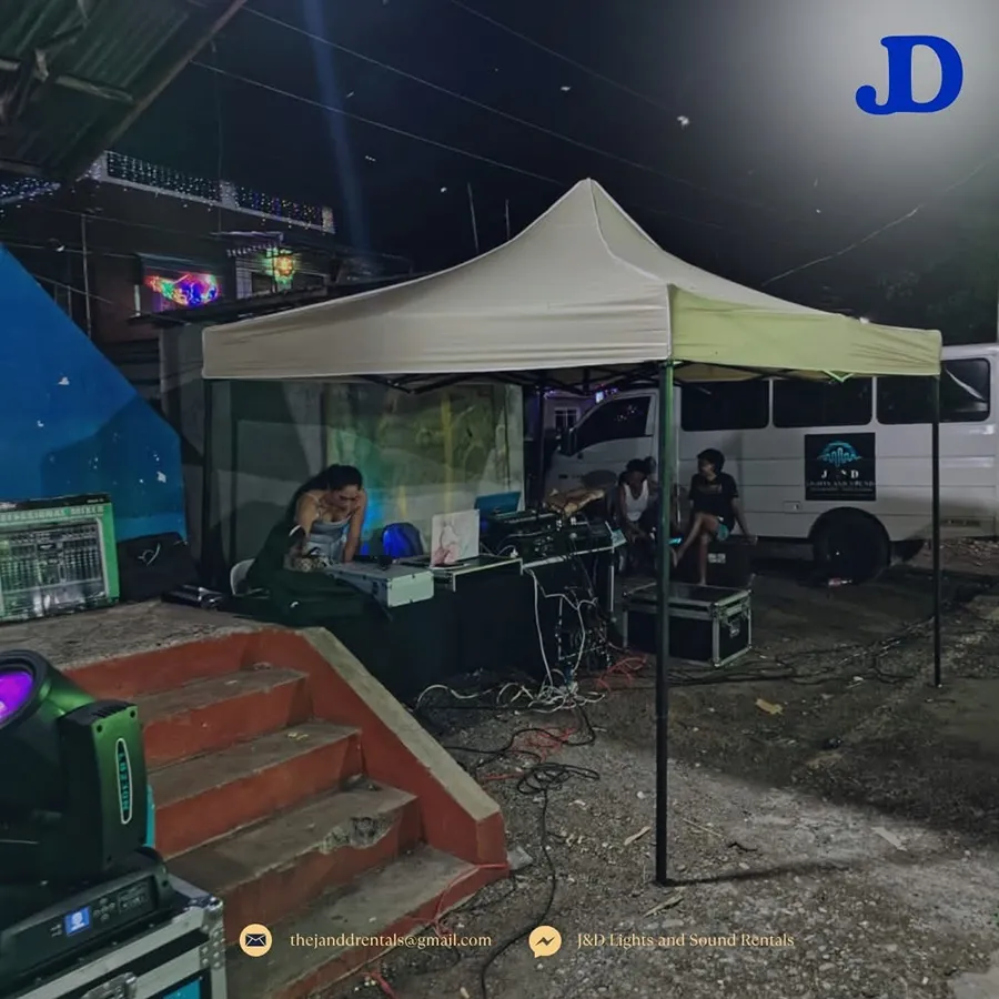 J&D lighting rig and a moving head fixture set up under a tent at a nighttime event