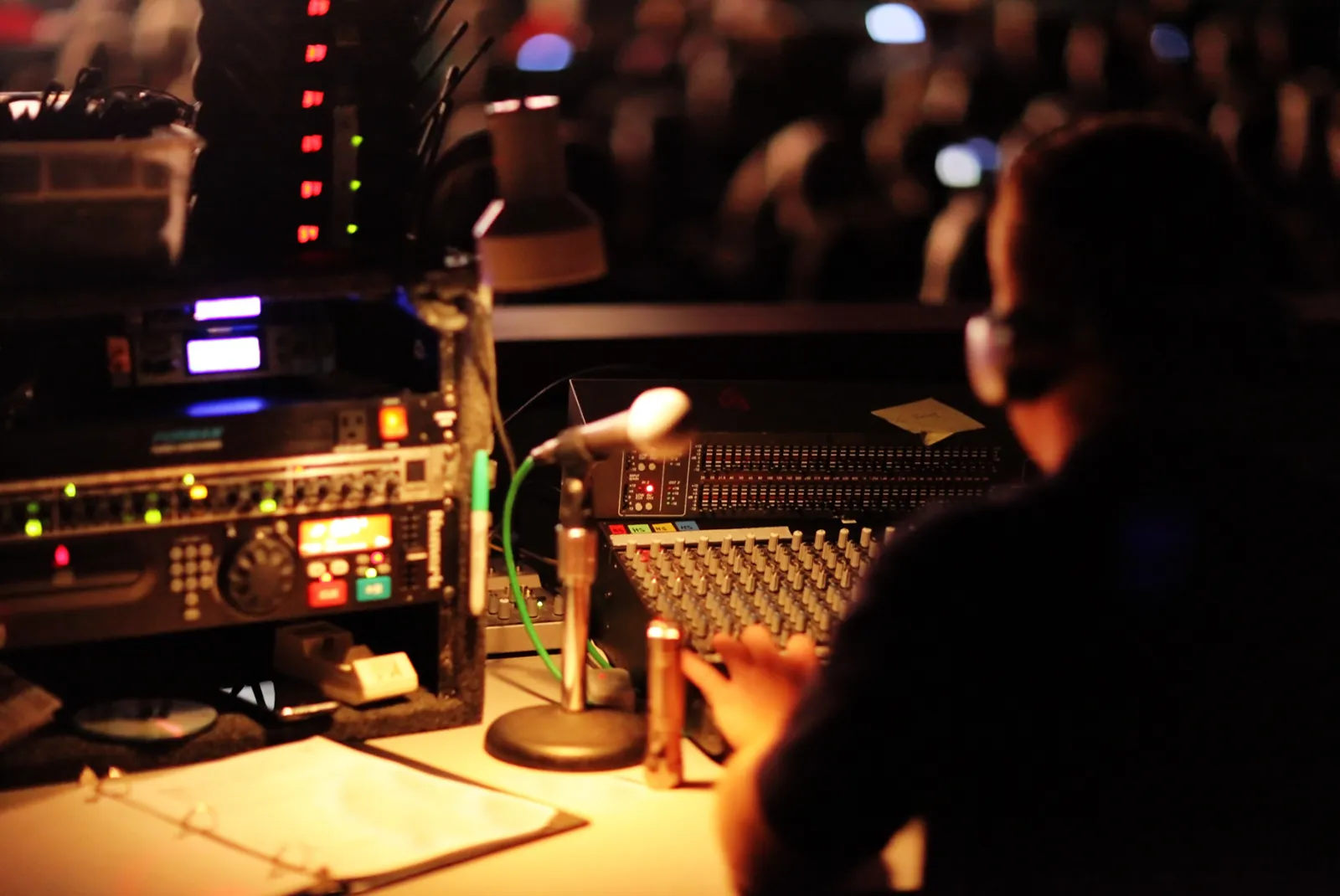 J&D sound engineer at the mixing console with headphones on, facing the crowd during an event